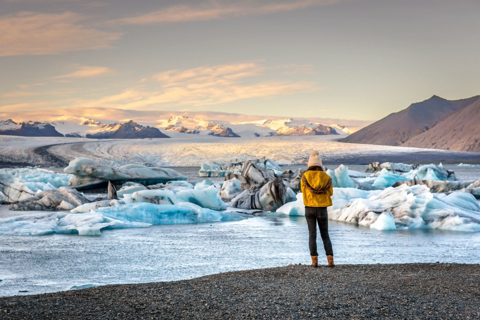 Jonge vrouw omhoog het kleden van koude kleren zien de verbazingwekkende Jokulsarlon, ijsberg lagoon in IJsland