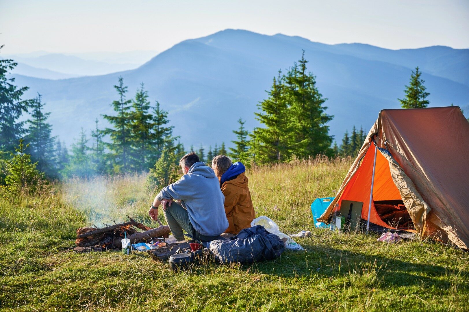 Scenic berg camping met twee tenten in de ochtend. Achteraanzicht van twee kampeerders die genieten van een sereen uitzicht op glooiende bergen. Schilderachtige zonsopgang landschap, het creëren van rustige en gezellige outdoor ervaring